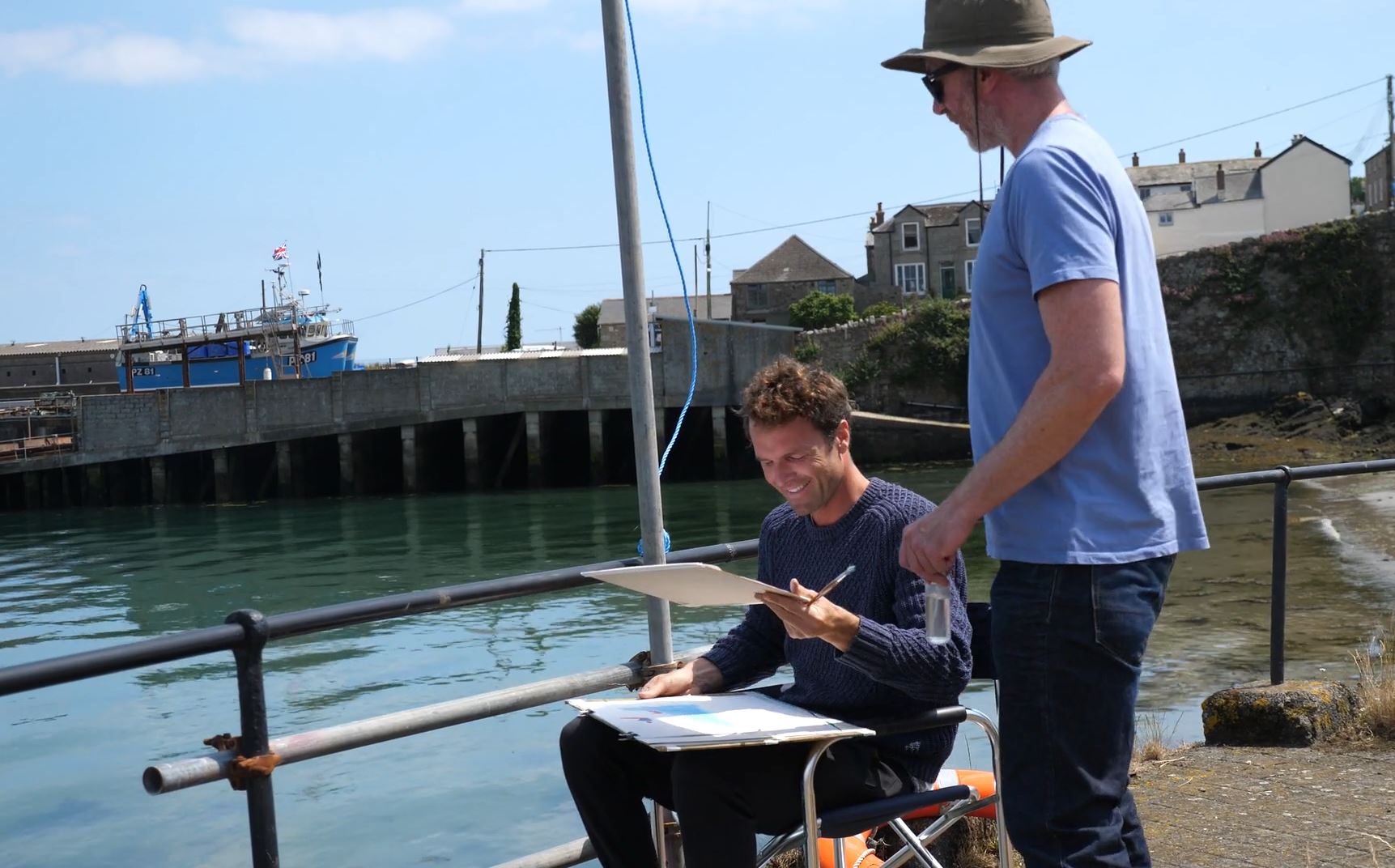 An art student smiling down at their work alongside Luke Frost